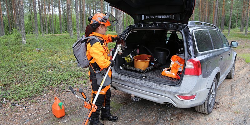 Sakari mantila pakkaa työvälineitään auton takakonttiin metsätien varressa. 