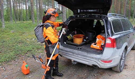 Sakari mantila pakkaa työvälineitään auton takakonttiin metsätien varressa. 